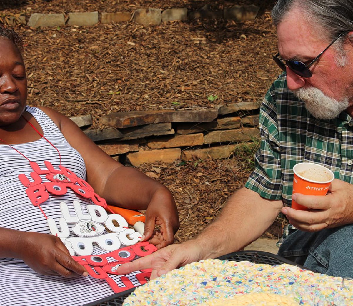 Zelma Griffith and Greg Wagstaff discuss Griffith’s rag rugs and her other crafts at Jittery Joe’s on Baxter Street in Athens, Ga. on Sept. 28, 2018. Wagstaff gave Griffith the idea to start making rag rugs. “I’m gonna tell you about my friend right here, he the one who got me hooked on making these. He told me about the idea. He really pretty much just throw’d it out the air. But I didn’t know what I was doing at first,” Griffith stated. (Photo by Kristen Adaway)