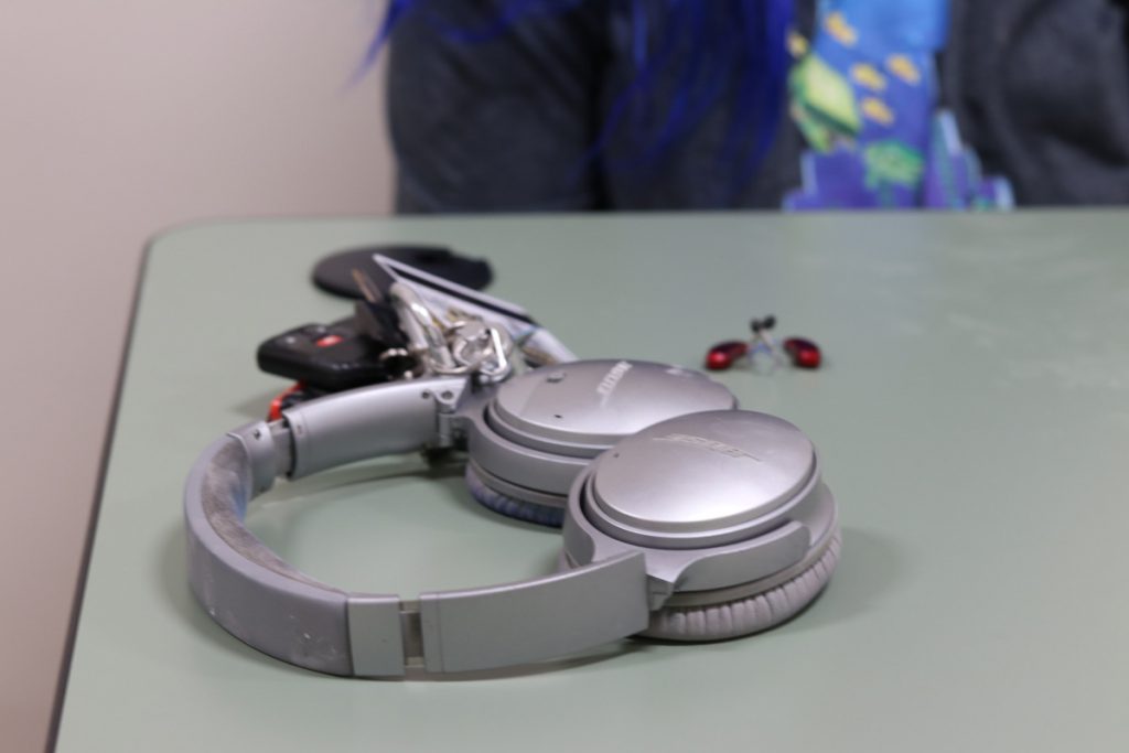 Silver headphones sit adjacent to red hearing aids on a gray table.