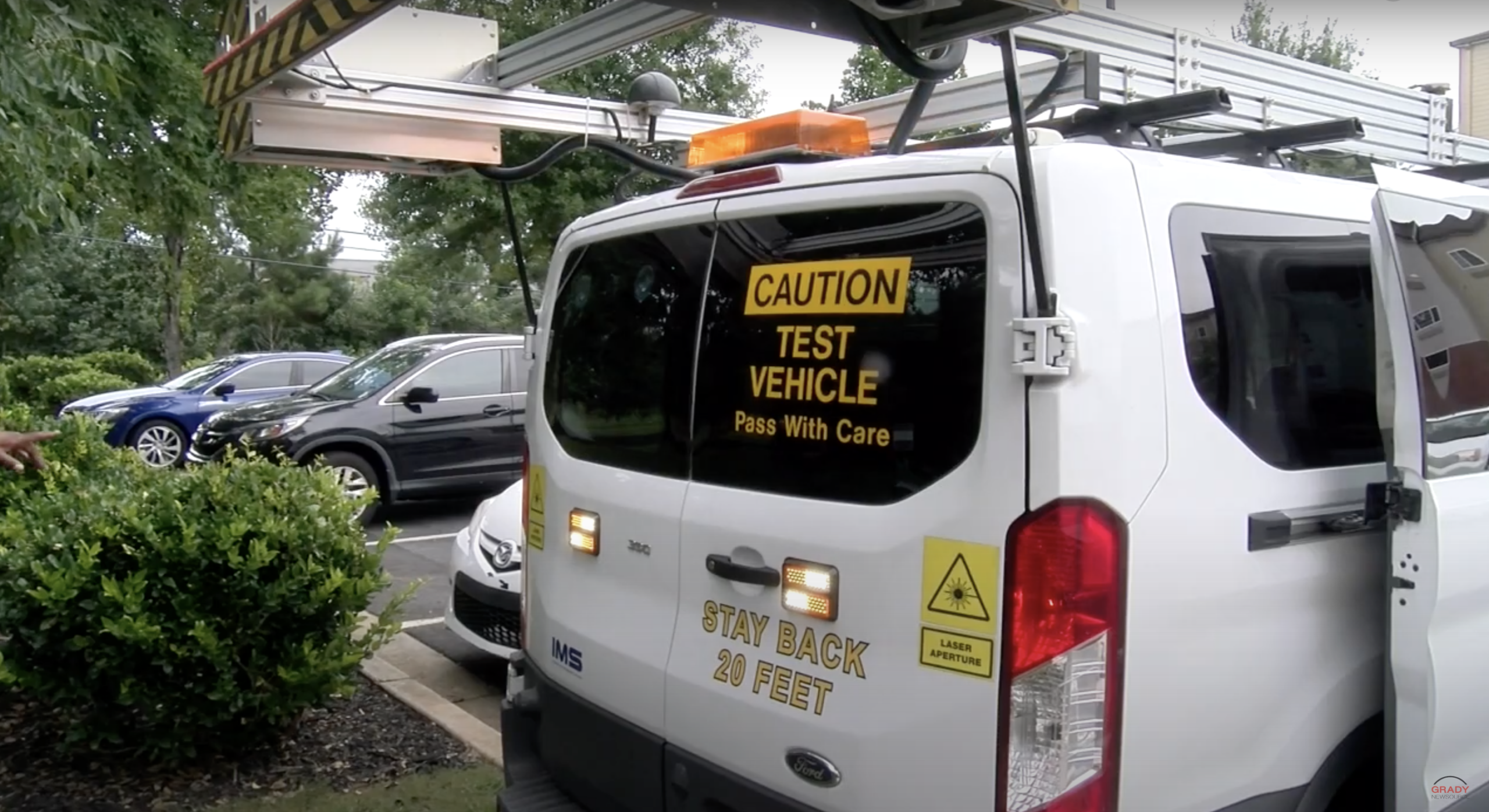 A white van equipped with lasers and flashing lights.