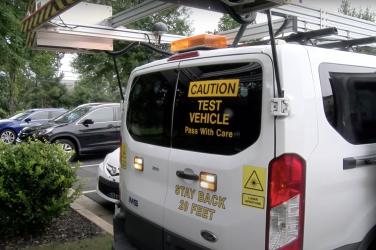 A white van equipped with lasers and flashing lights.