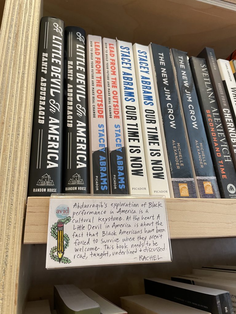 Books on shelf with book review on notecard in front of them.