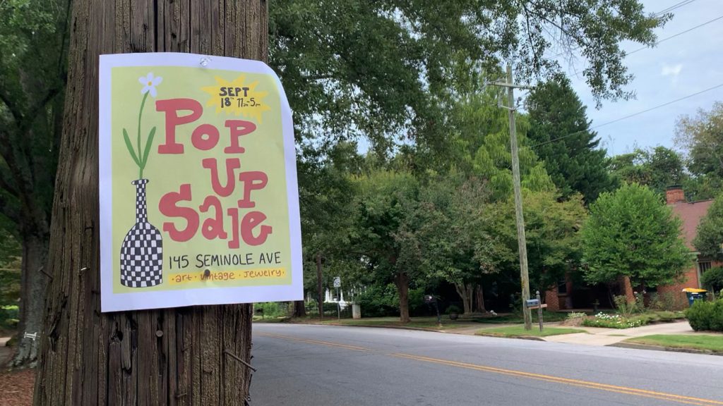 A paper sign that reads "Pop Up Sale" hangs on a wooden telephone pole next to an empty street