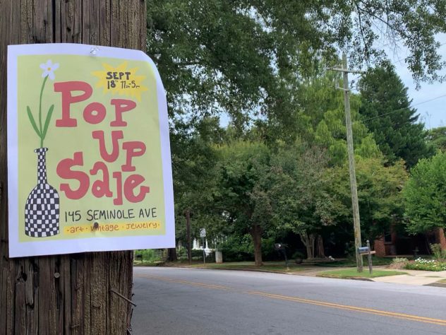 A paper sign that reads "Pop Up Sale" hangs on a wooden telephone pole next to an empty street