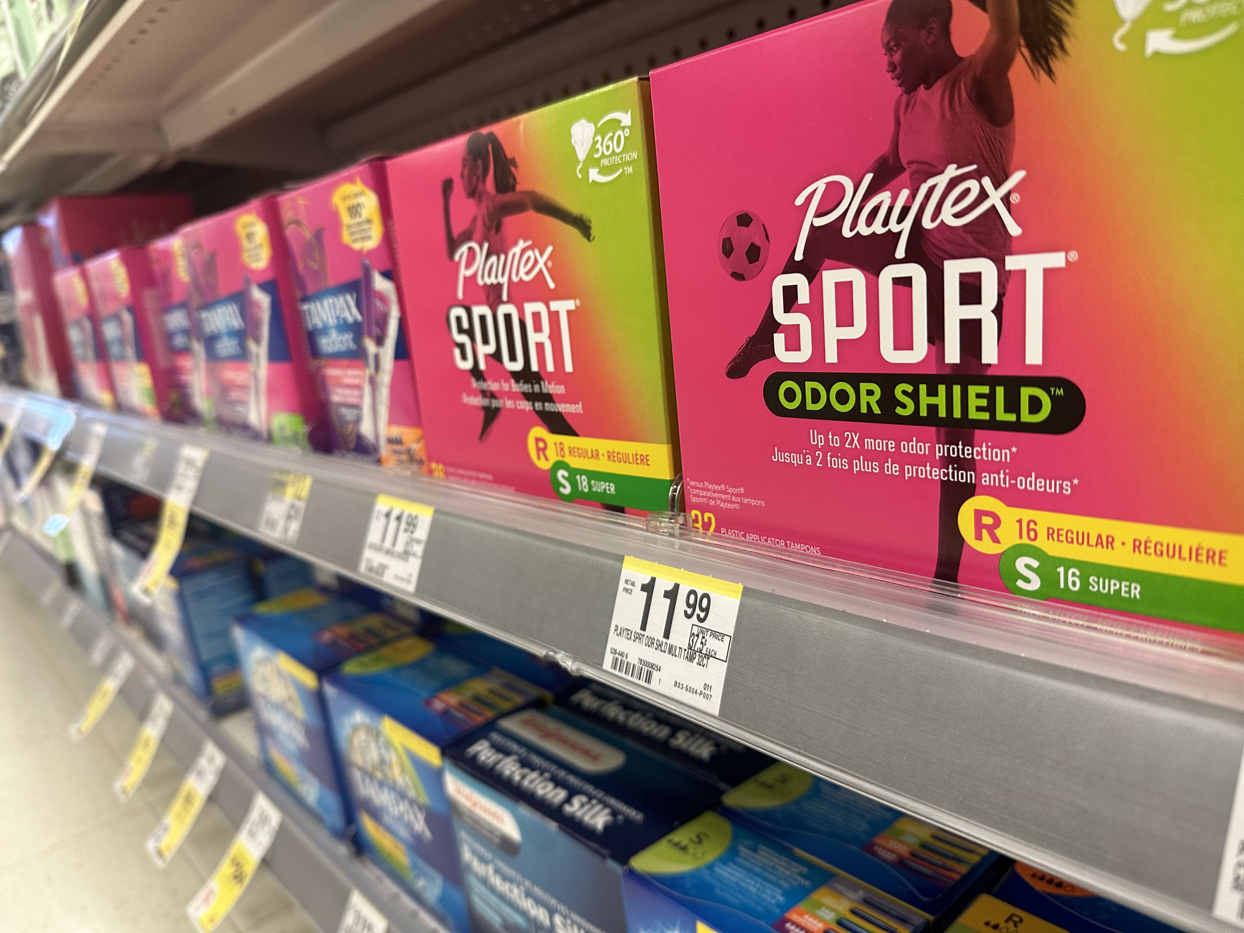 Colorful boxes of tampons sit on a store shelf. Their yellow price tags are visible.