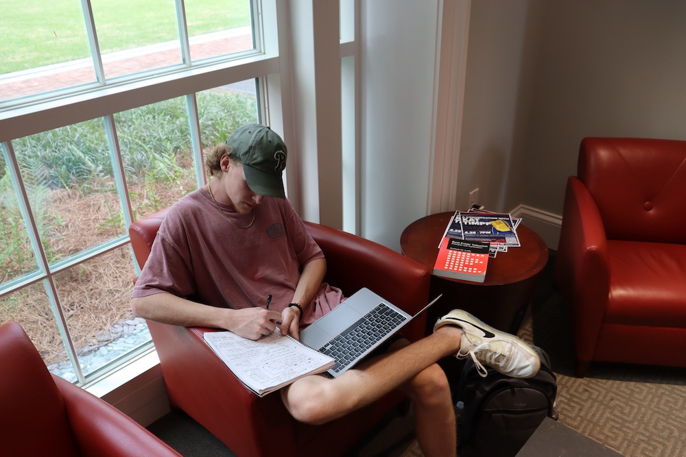 University of Georgia student Jack Gilmartin looks at his laptop and writes in his notebook.