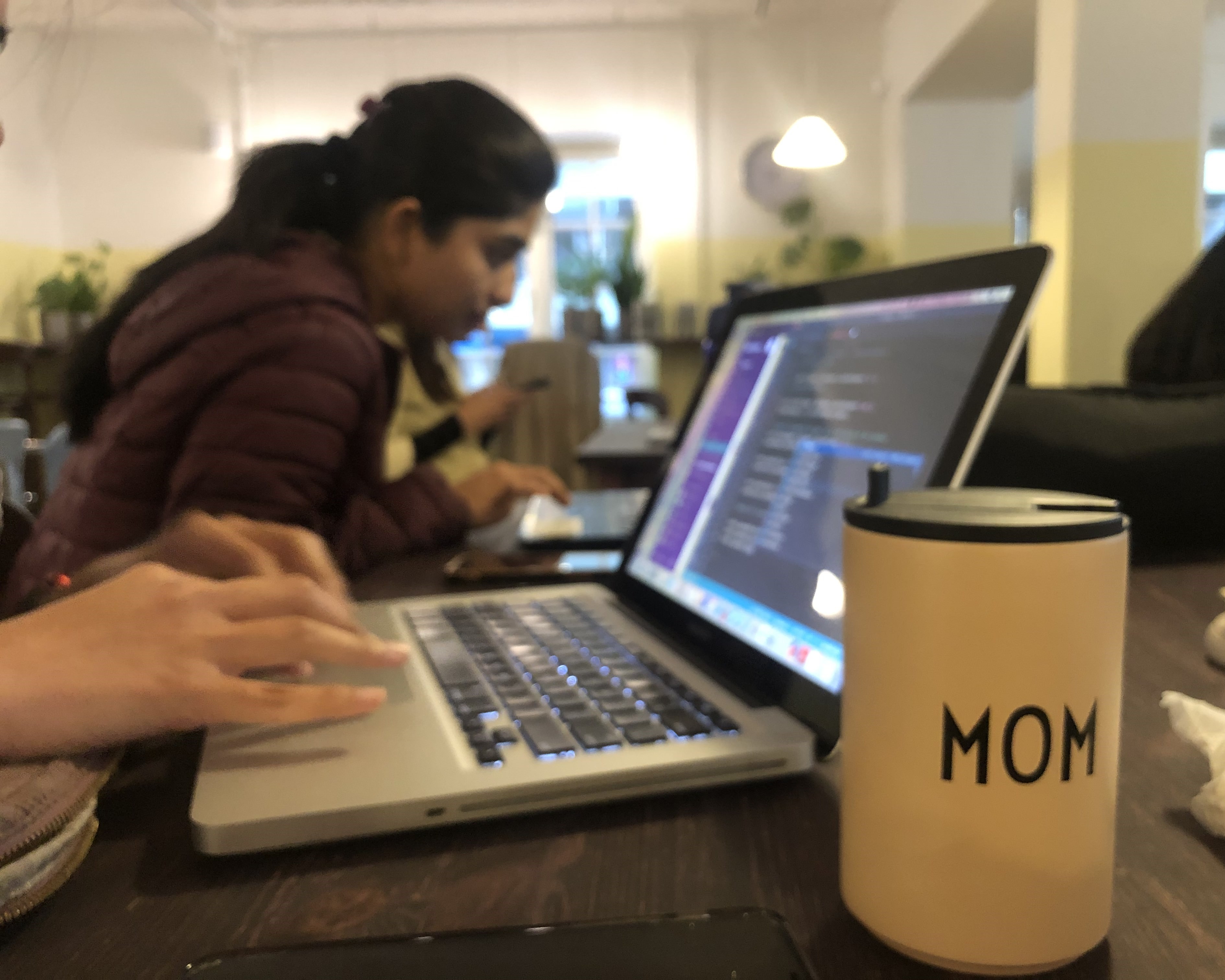 A student works at her computer at the ReDI School with a thermos that says "Mom."