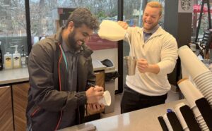 Prince Market managers Yash Patel (left) and Ryan Vetter (right) craft a beverage for a customer at the coffee bar, featuring a selection of Starbucks products.