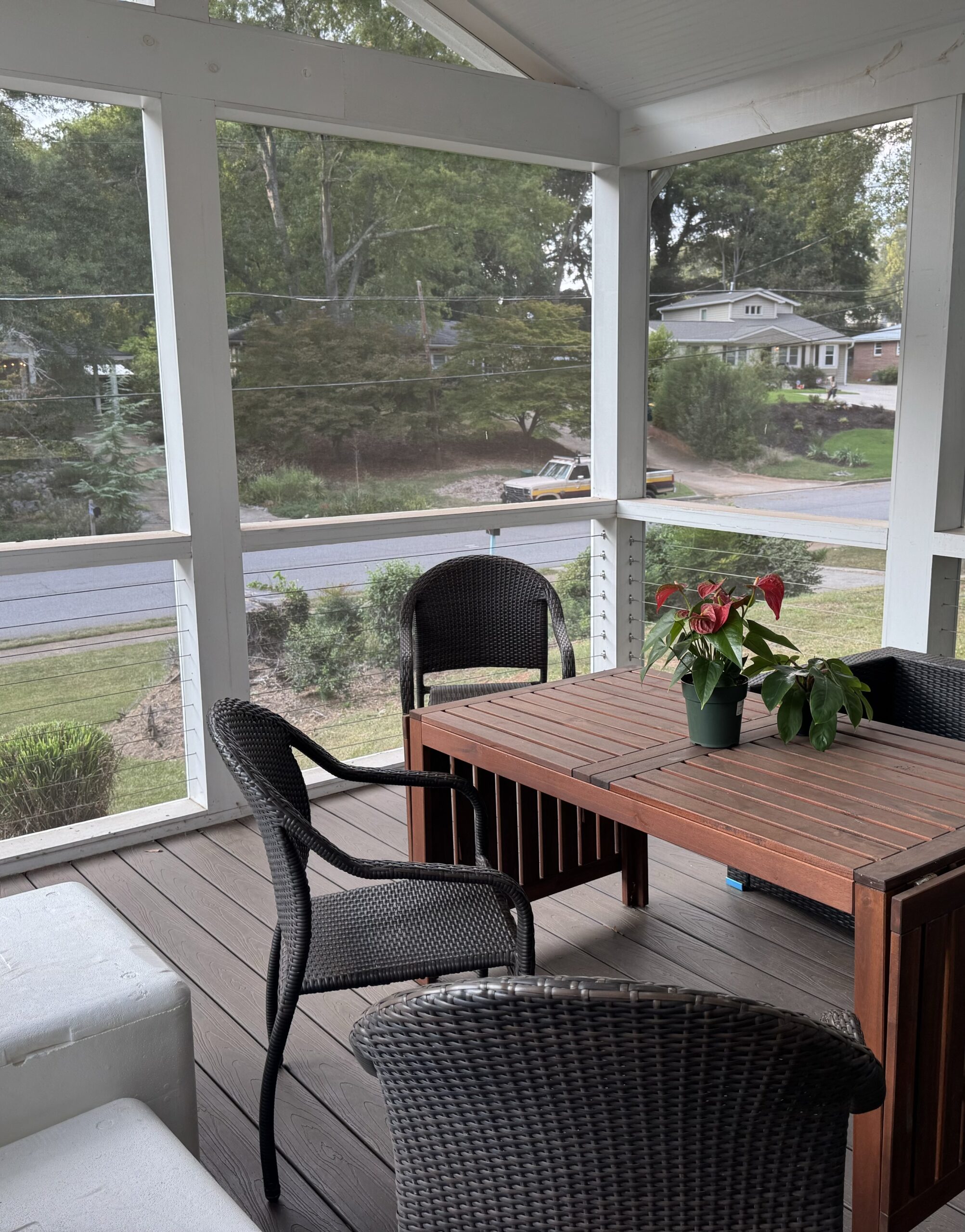 A screened-in porch with a table and chairs.