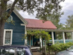 The exterior of a blue house with a red roof.