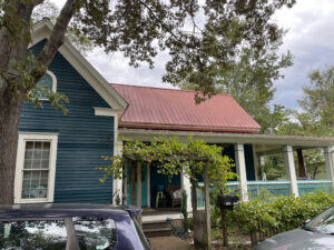 The exterior of a blue house with a red roof.