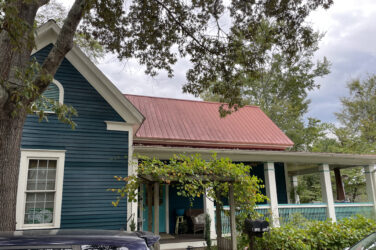 The exterior of a blue house with a red roof.