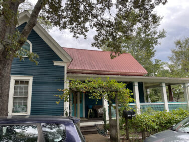 The exterior of a blue house with a red roof.