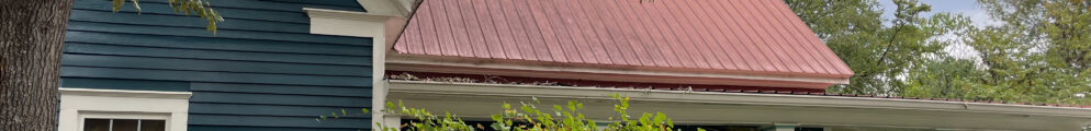 The exterior of a blue house with a red roof.