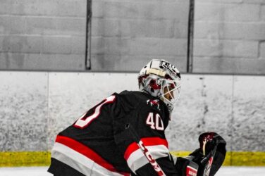 A hockey goalie catches a puck.