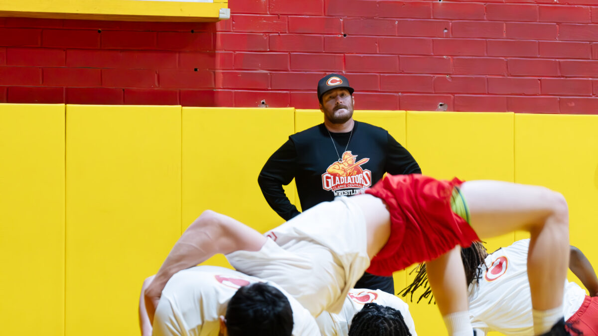 A wrestling coach supervises practice.