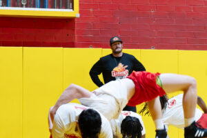 A wrestling coach supervises practice.