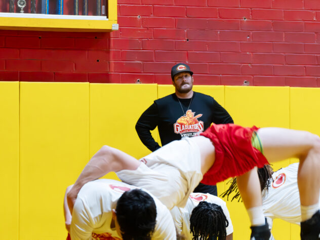 A wrestling coach supervises practice.