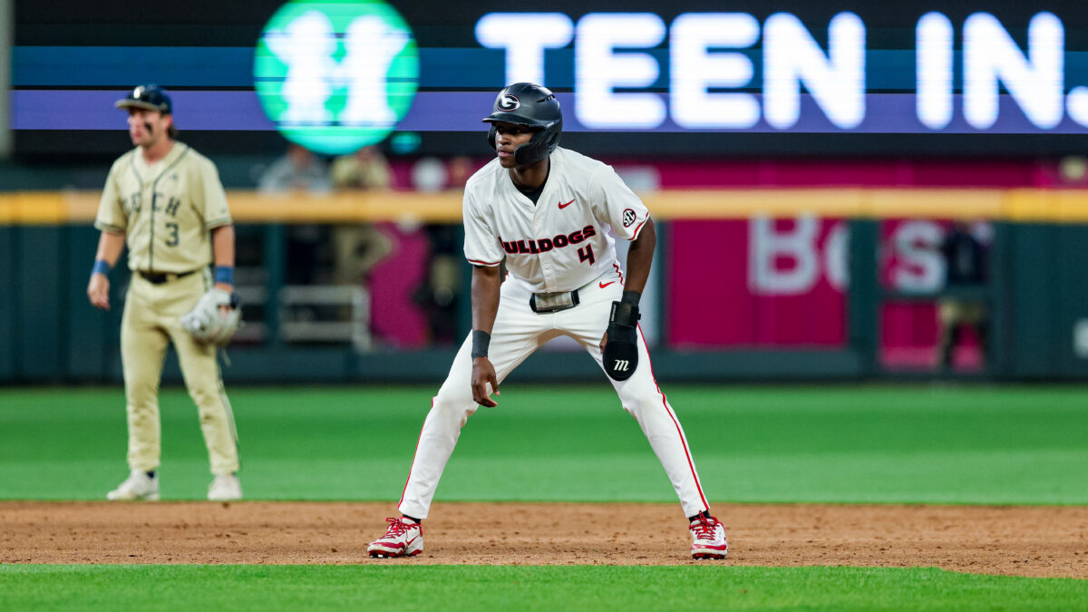 A baseball player takes a lead off first base.