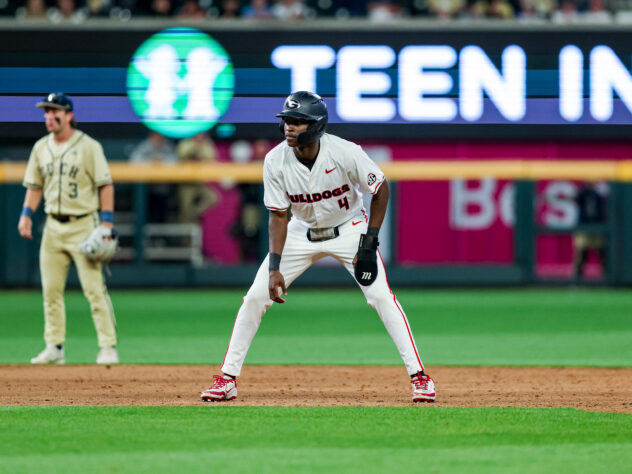 A baseball player takes a lead off first base.