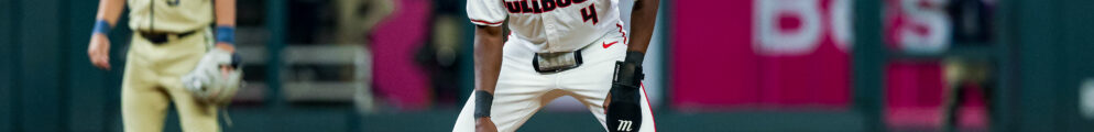 A baseball player takes a lead off first base.