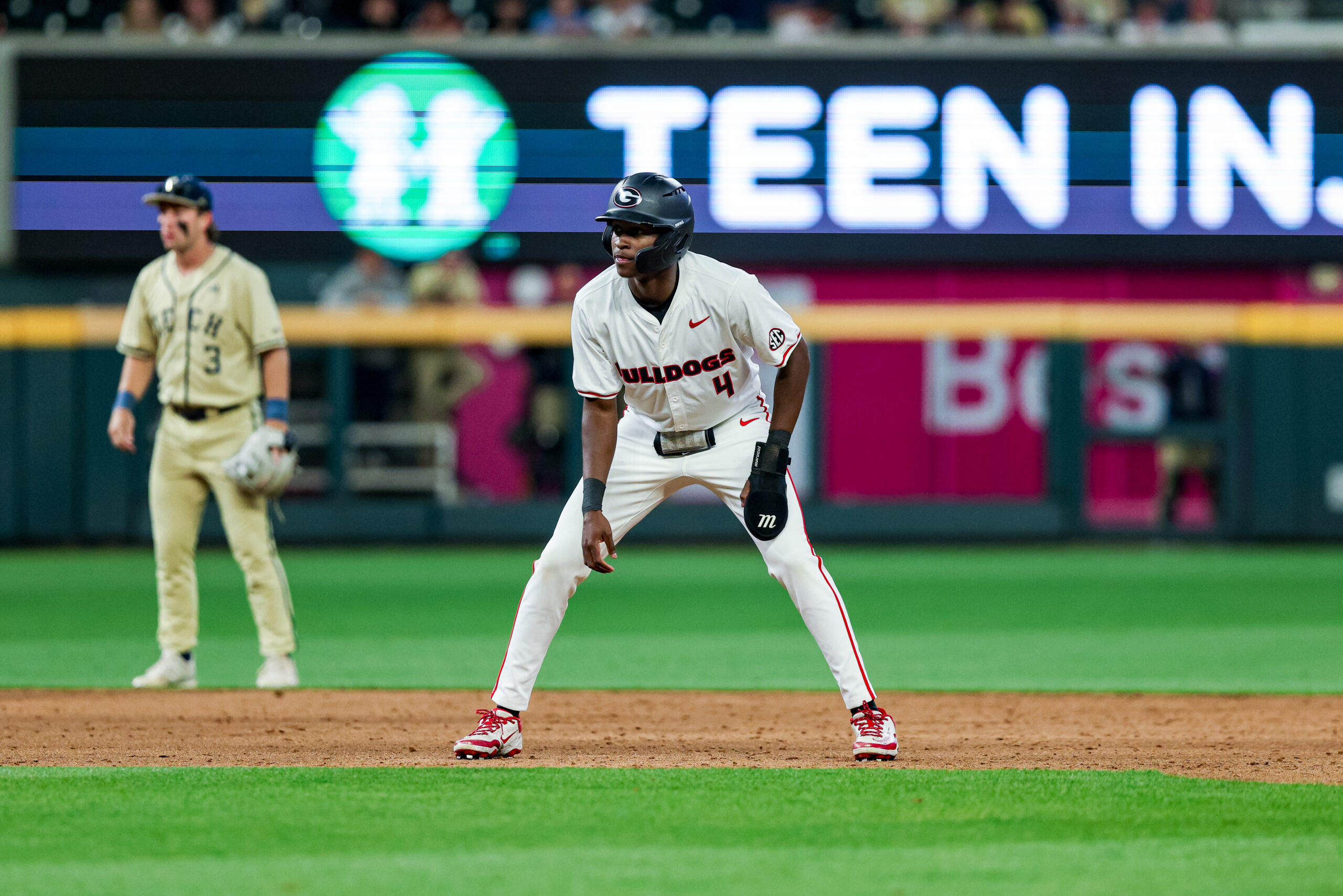 A baseball player takes a lead off first base.