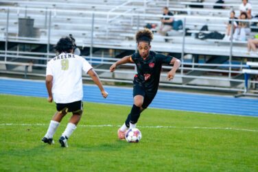 A soccer player dribbles against an opponent