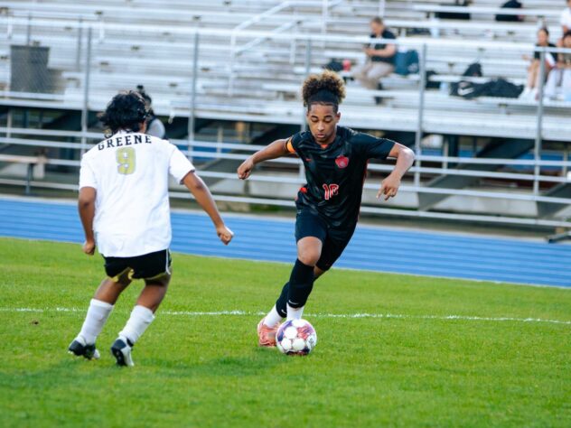 A soccer player dribbles against an opponent