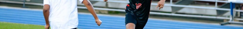 A soccer player dribbles against an opponent