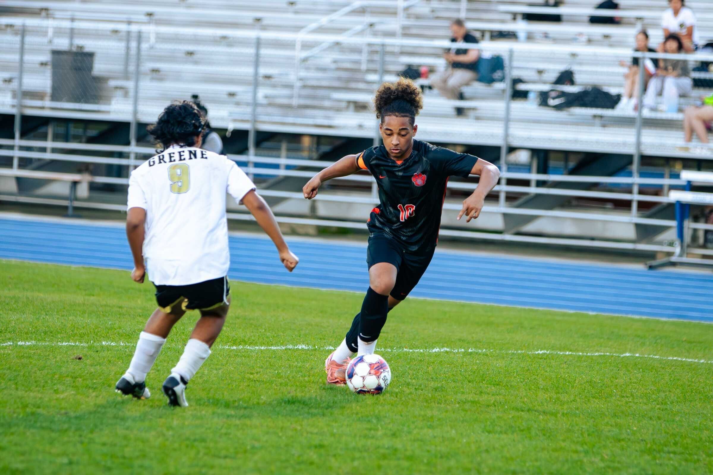 A soccer player dribbles against an opponent
