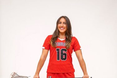 A lacrosse player poses with her stick.