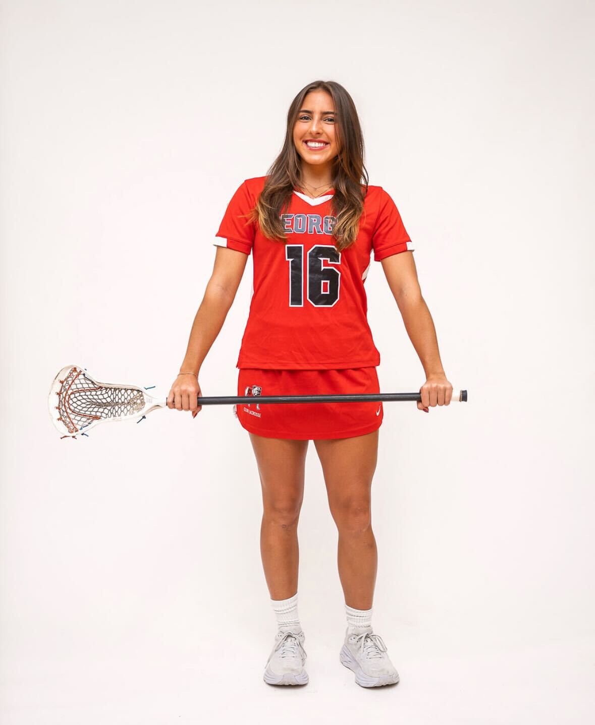 A lacrosse player poses with her stick.