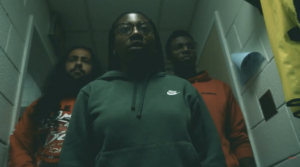 Three people stand in a dark hallway