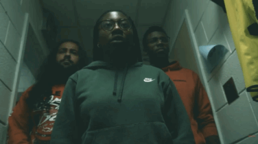 Three people stand in a dark hallway