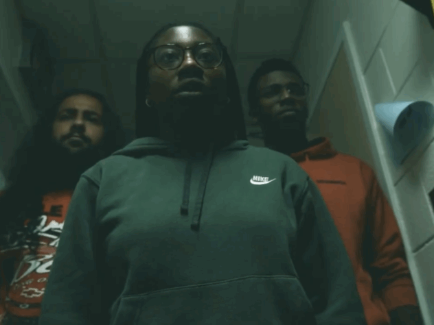 Three people stand in a dark hallway