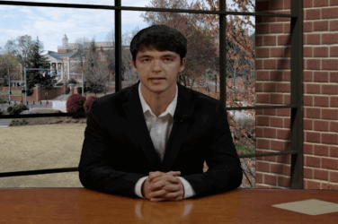 A sports anchor sits at the newsroom desk