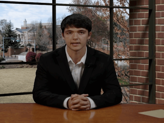 A sports anchor sits at the newsroom desk
