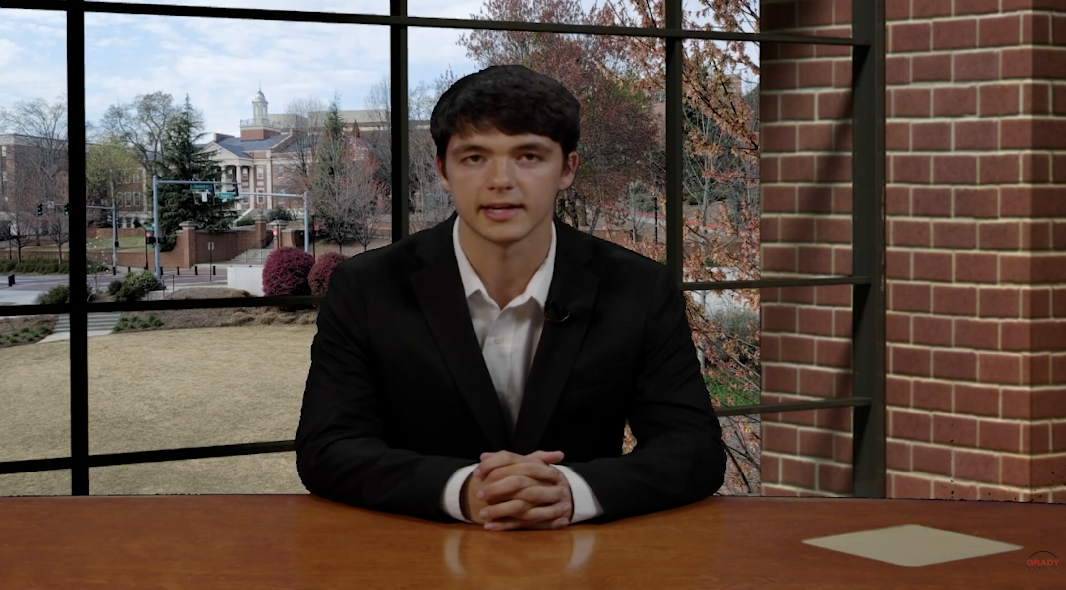 A sports anchor sits at the newsroom desk