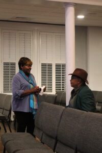 Two people talk, a woman and man, at a public meeting