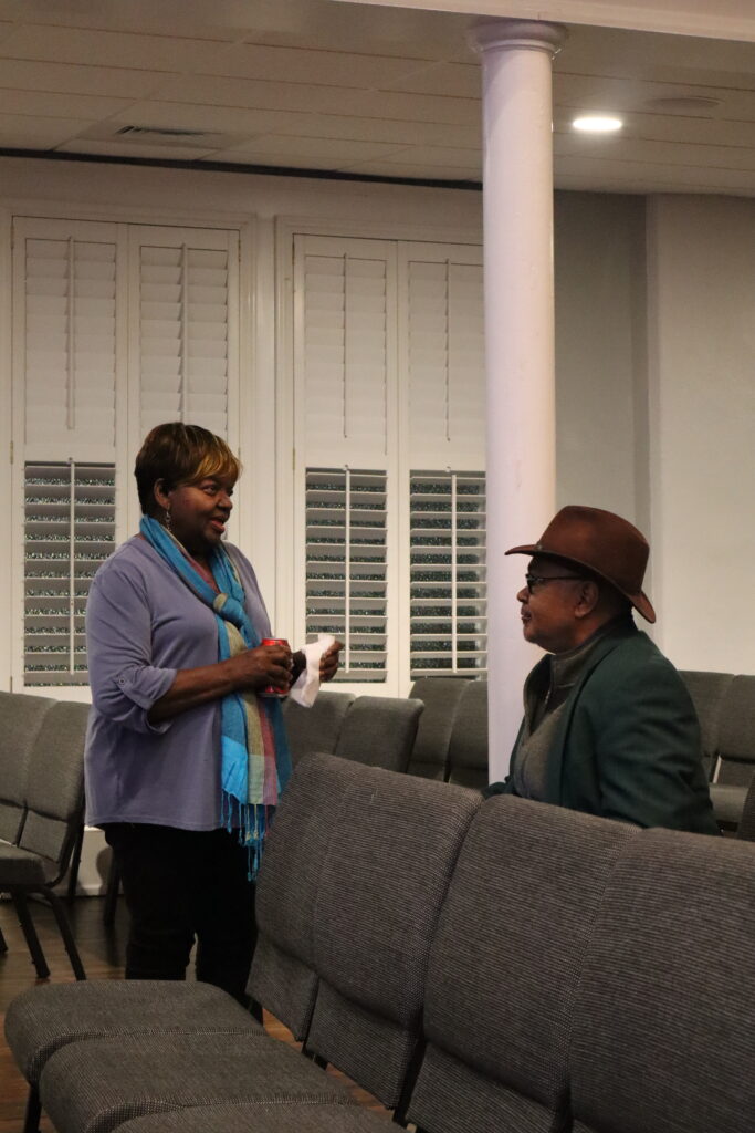 Two people talk, a woman and man, at a public meeting