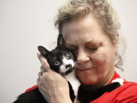 A woman cuddles a stray cat.
