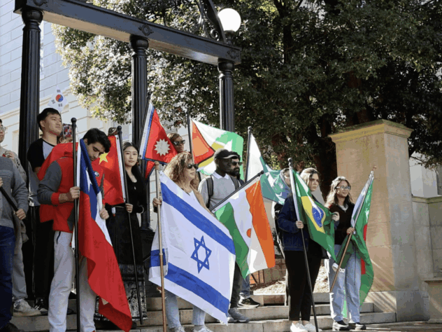 Group of students holding flags in front of the UGA arch