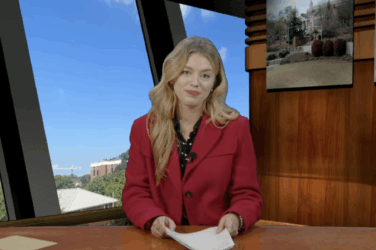 Anchor sits at a news desk