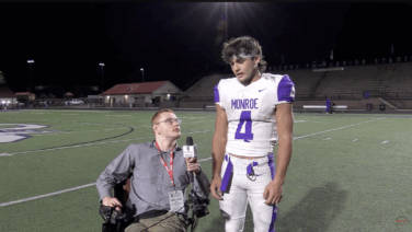 Sports reporter interviewing football player on the field