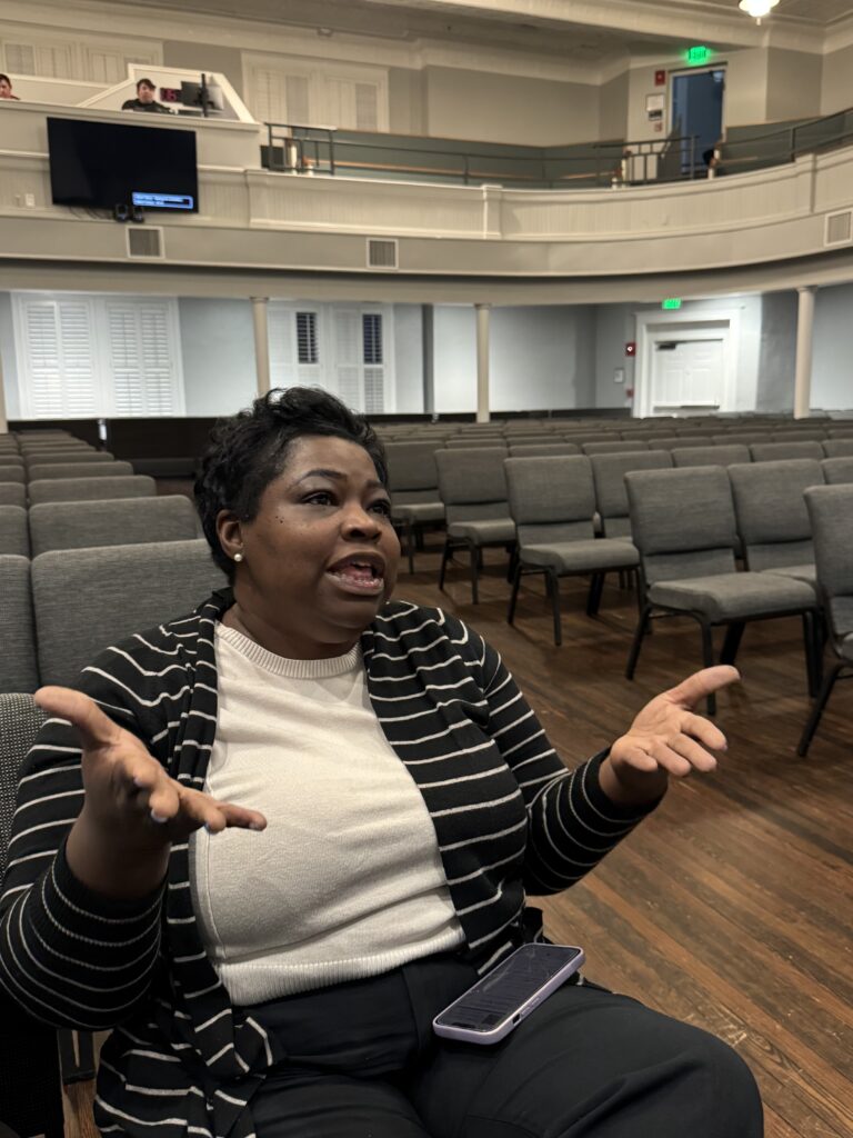 Woman gestures with her hands open while sitting in the seats at the Clarke County School District building.