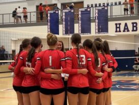A group of volleyball players huddles before a match.