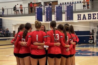 A group of volleyball players huddles before a match.