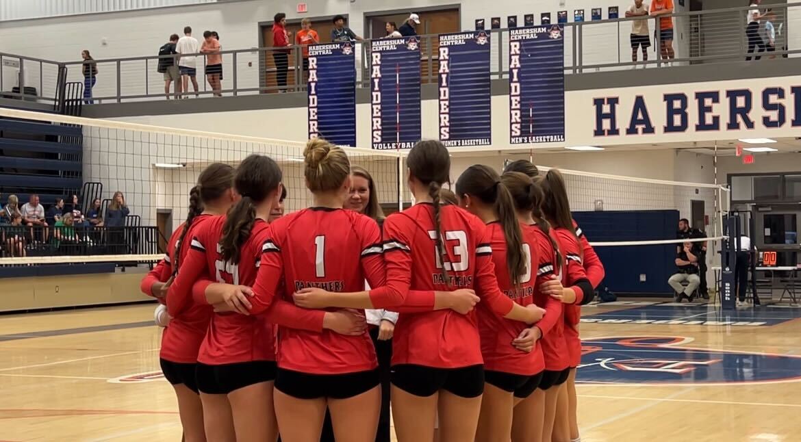 A group of volleyball players huddles before a match.