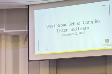 Woman stands at a podium in the Clarke County School District building on stage.