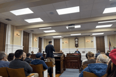 Man stands during a commission meeting in Athens.