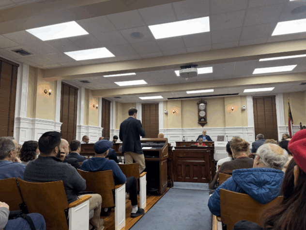 Man stands during a commission meeting in Athens.